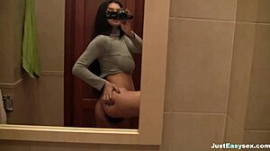 busty babe fingers her hairy pussy in the bathroom