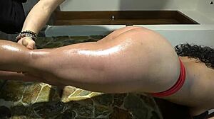 Detailed view of oiled beautiful butt and legs in red and dark blue panties during massage