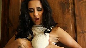 Glamcore babe in bikini strips on sofa with long hair and tattoo