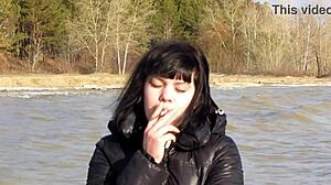 Look at this cute milf smoking a cigarette outdoors. She's showing her shaved pussy with dildo inside and tits in public fetish style.