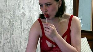 brunette housewife in red lingerie and stockings sucks candy while watching movie on bed