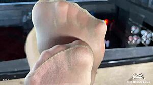 mistress's beautiful feet in flesh-colored pantyhose tease you close-up on the desk