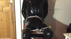 masked latex slave cuffed in tight bondage trim
