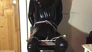 masked latex slave cuffed in tight bondage trim
