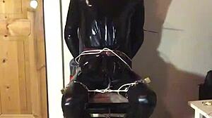 masked latex slave cuffed in tight bondage trim