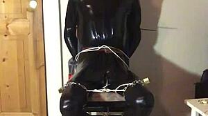 masked latex slave cuffed in tight bondage trim