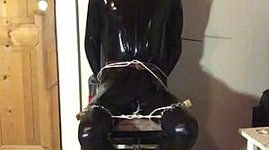 masked latex slave cuffed in tight bondage trim