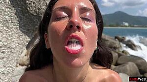 Goldene Dusche auf nasses Brünetten-Gesicht vor heißem öffentlichem Strandsex mit Paar